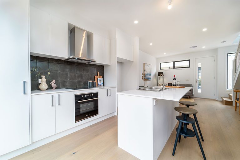 Centenary, Seaford: a kitchen with white cabinets and black appliances